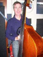 The AJ Jazz Band jazz band double bass player looking into the camera.  The band play jazz standards