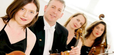 The NC String Quartet Quartet in smart black smiling at camera. They play in Tyne & Wear